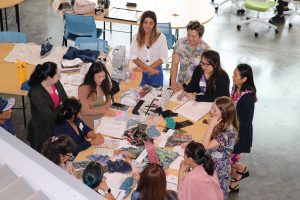 Group of people involved in an educator externship in the creative industries looking at sketches and different fabric swatches